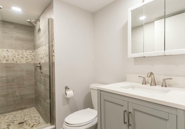 bathroom with vanity, toilet, and tiled shower