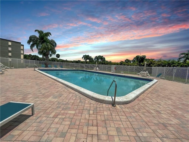 pool at dusk with a patio area