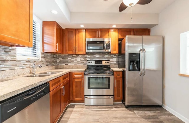 kitchen with sink, ceiling fan, stainless steel appliances, light hardwood / wood-style floors, and decorative backsplash