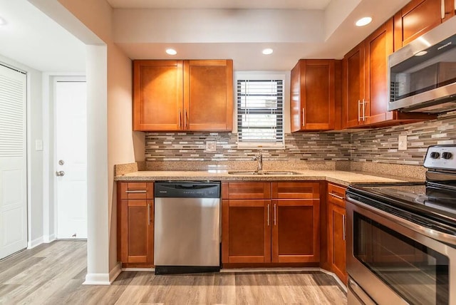 kitchen featuring light stone counters, sink, stainless steel appliances, and light hardwood / wood-style floors