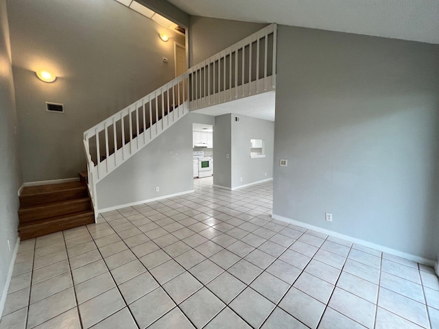 unfurnished living room with light tile patterned flooring and high vaulted ceiling