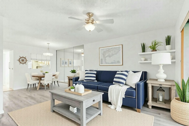 living room with ceiling fan, light hardwood / wood-style floors, and a textured ceiling