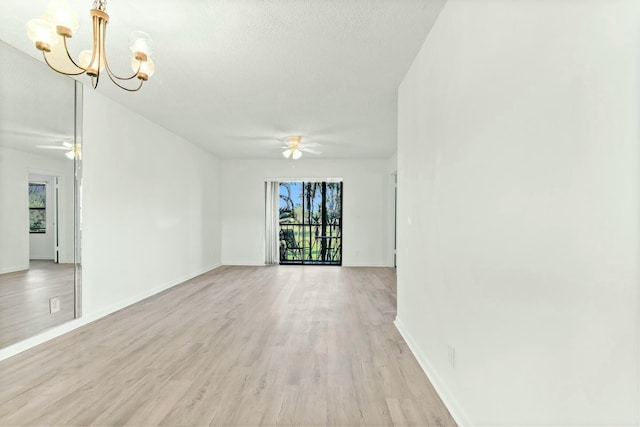 unfurnished room with ceiling fan with notable chandelier, a textured ceiling, and light wood-type flooring