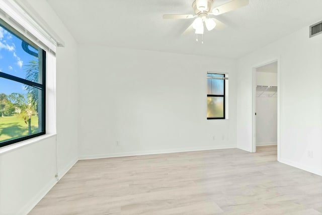 empty room featuring ceiling fan, a healthy amount of sunlight, and light hardwood / wood-style floors