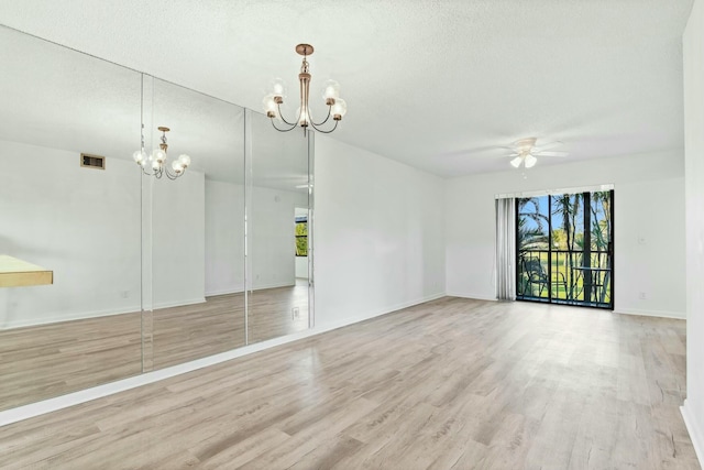 unfurnished room with ceiling fan with notable chandelier, light hardwood / wood-style floors, and a textured ceiling