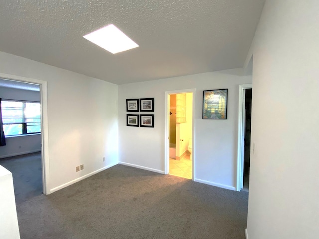 spare room with dark colored carpet and a textured ceiling