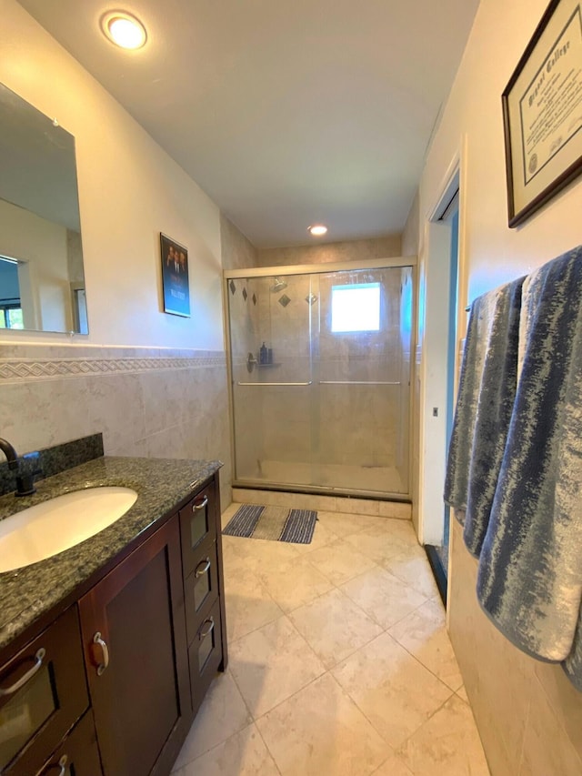 bathroom featuring walk in shower, vanity, and tile walls