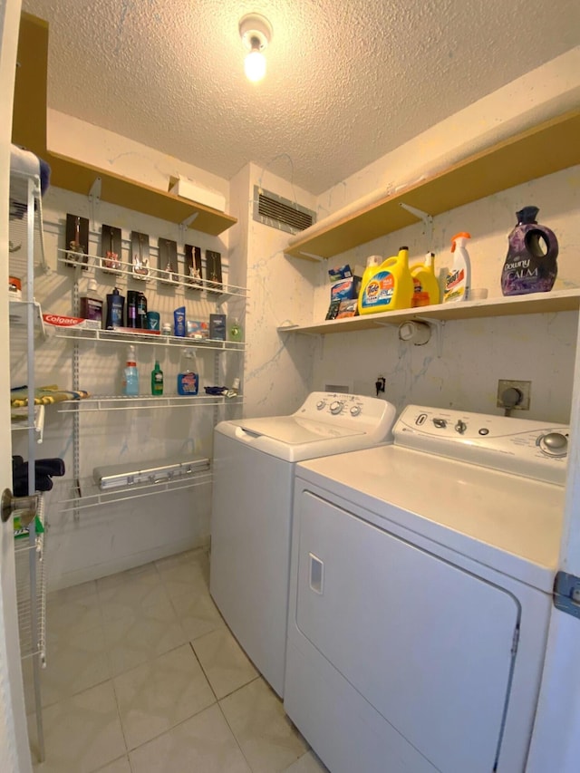 laundry area with separate washer and dryer, light tile patterned floors, and a textured ceiling