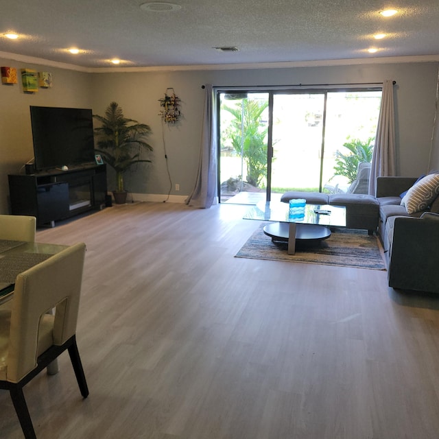 living room with crown molding, hardwood / wood-style floors, a textured ceiling, and a healthy amount of sunlight