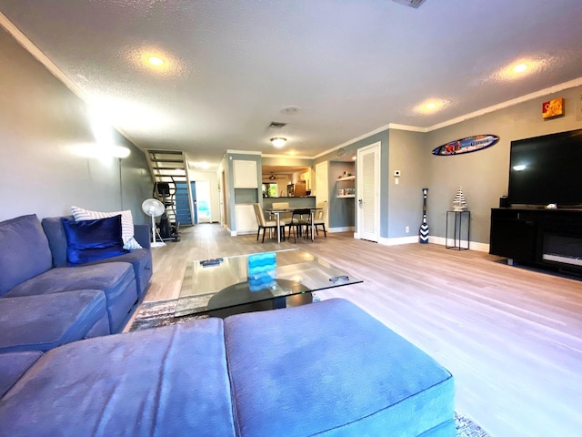 living room featuring crown molding, a textured ceiling, and light wood-type flooring