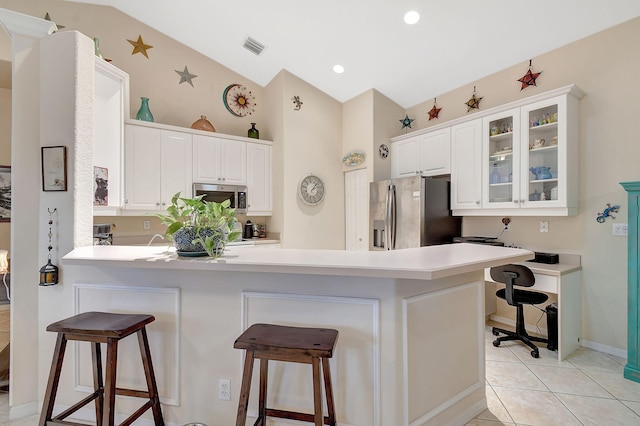 kitchen featuring stainless steel appliances, kitchen peninsula, a breakfast bar area, and white cabinets