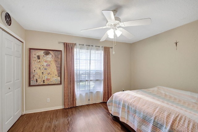 bedroom with dark wood-type flooring, ceiling fan, and a closet