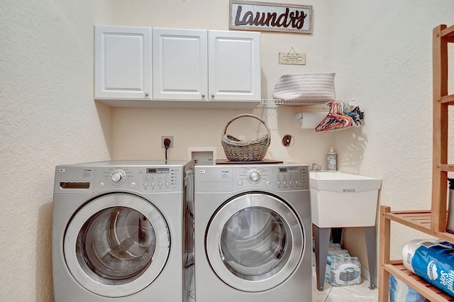 laundry room with cabinets, washer and clothes dryer, and light tile patterned floors