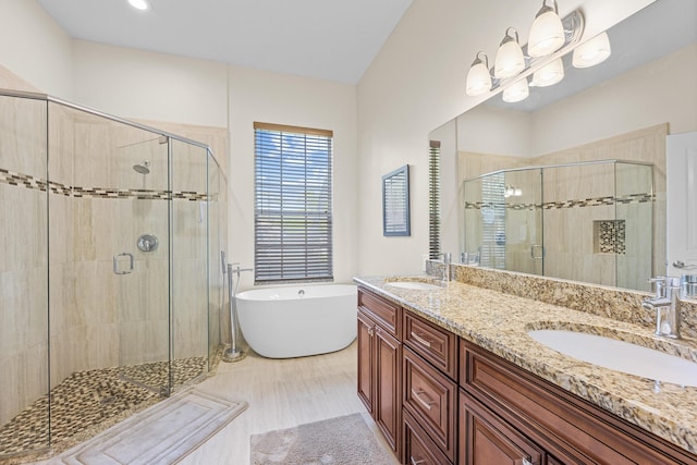 full bath featuring a freestanding bath, a shower stall, double vanity, and a sink