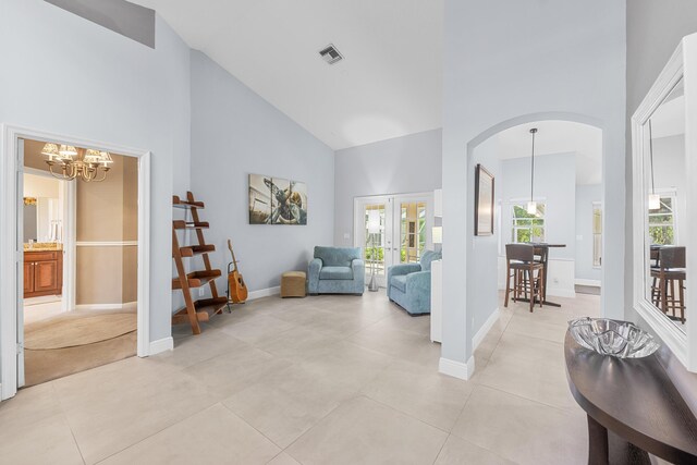 tiled living room with an inviting chandelier, high vaulted ceiling, and french doors