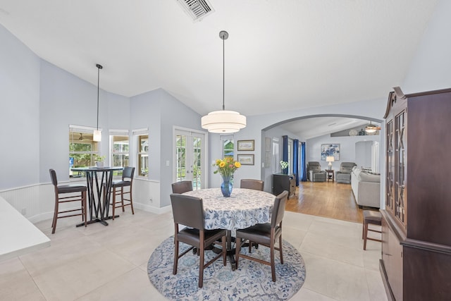 dining area featuring visible vents, vaulted ceiling, light tile patterned floors, french doors, and arched walkways