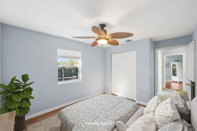 bedroom featuring a ceiling fan, wood finished floors, baseboards, visible vents, and a closet