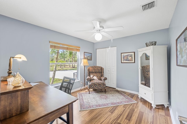 office space with visible vents, baseboards, a ceiling fan, and wood finished floors