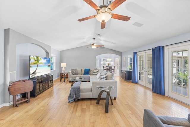 living area with visible vents, lofted ceiling, arched walkways, french doors, and light wood-type flooring