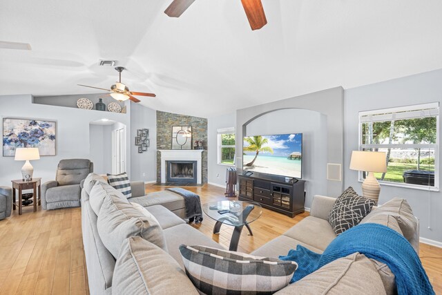 living room featuring ceiling fan, a large fireplace, lofted ceiling, and light hardwood / wood-style flooring