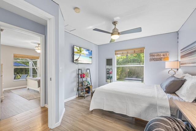 bedroom with a ceiling fan, wood finished floors, and baseboards