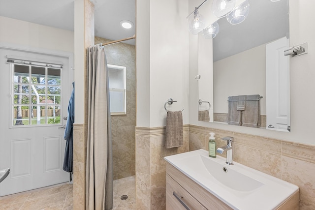 bathroom featuring a wainscoted wall, a walk in shower, tile walls, and vanity