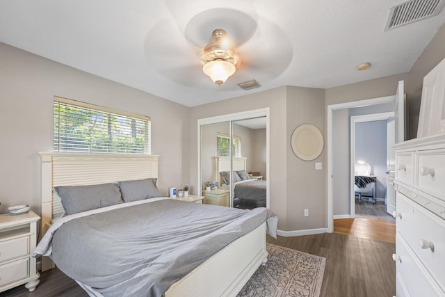 bedroom featuring dark wood finished floors, baseboards, visible vents, and a closet