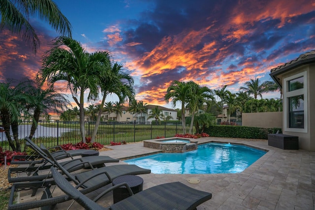 pool at dusk featuring an in ground hot tub, a water view, and a patio