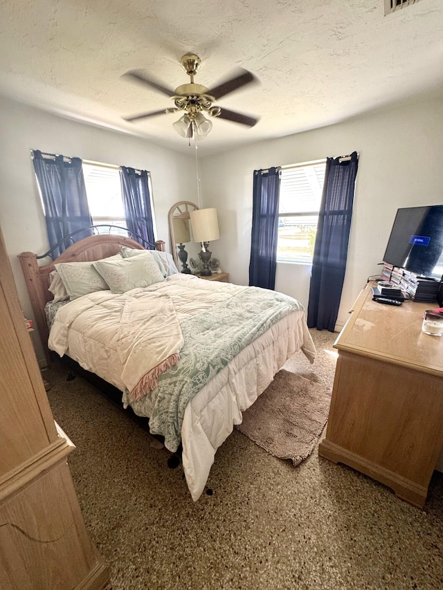 bedroom featuring multiple windows, ceiling fan, and a textured ceiling