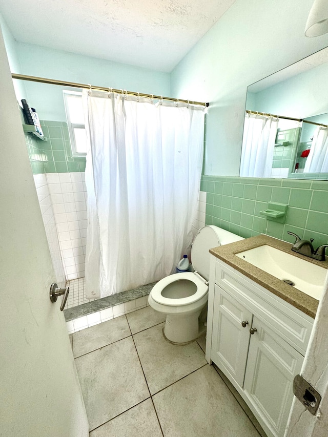 bathroom featuring walk in shower, tile patterned floors, tile walls, a textured ceiling, and vanity