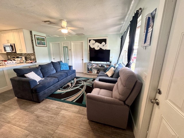 living room featuring ceiling fan and a textured ceiling