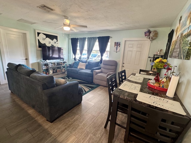 living room featuring ceiling fan and a textured ceiling