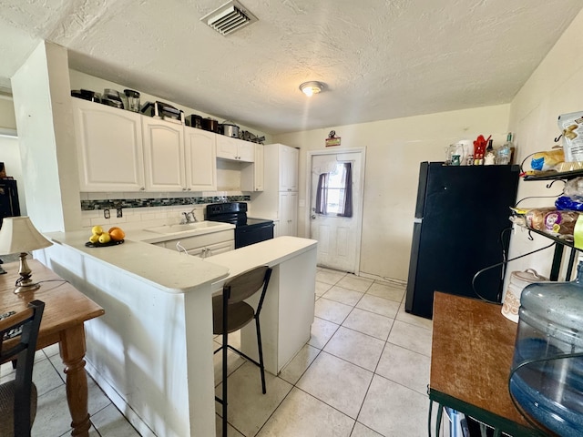 kitchen featuring light tile patterned flooring, black appliances, white cabinetry, a kitchen breakfast bar, and kitchen peninsula