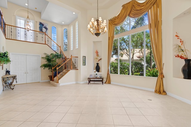 tiled foyer entrance featuring a towering ceiling, plenty of natural light, and a chandelier