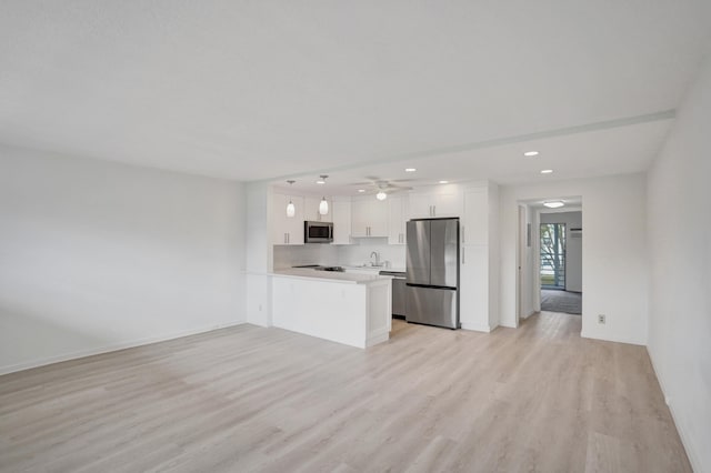 kitchen featuring appliances with stainless steel finishes, kitchen peninsula, ceiling fan, light hardwood / wood-style floors, and white cabinets