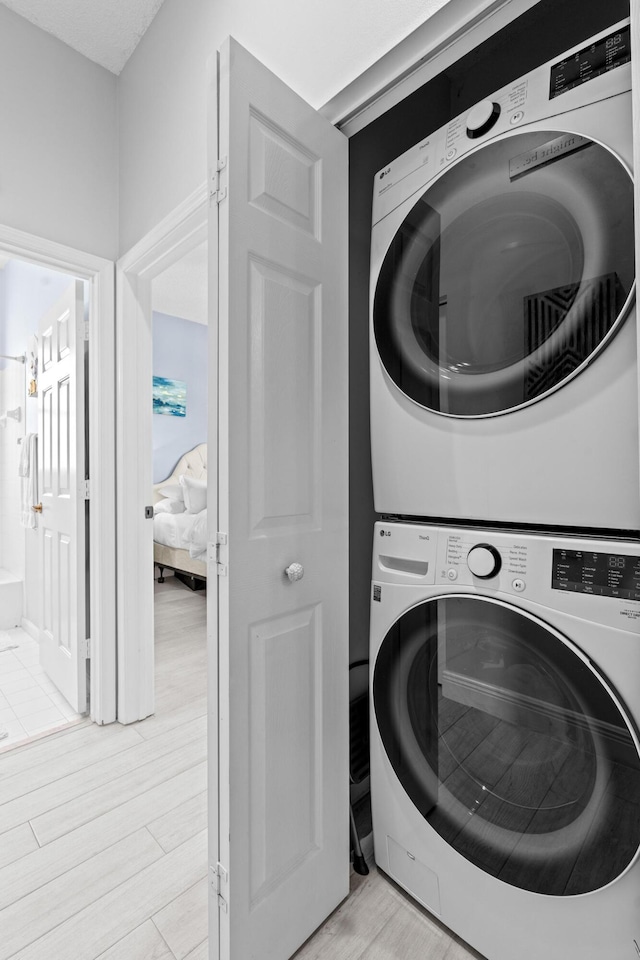 washroom featuring stacked washer / drying machine and light hardwood / wood-style flooring