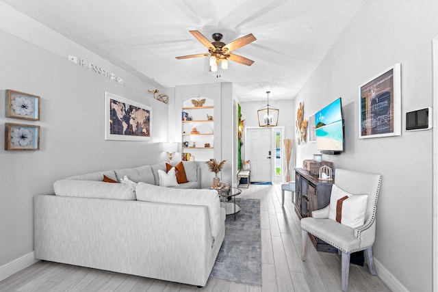 living room featuring ceiling fan, a textured ceiling, and light hardwood / wood-style floors