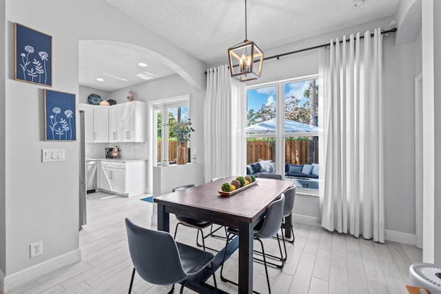 dining space featuring a notable chandelier, a textured ceiling, and light hardwood / wood-style floors