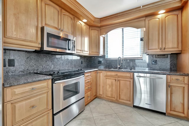 kitchen with sink, backsplash, dark stone counters, and appliances with stainless steel finishes