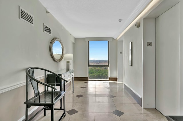 hallway with light tile patterned floors, a textured ceiling, and elevator