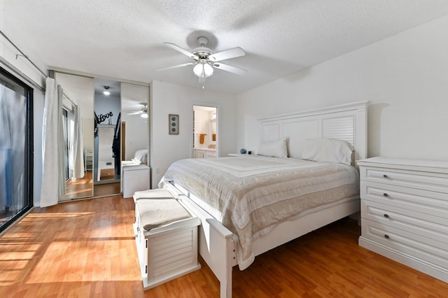 bedroom with hardwood / wood-style flooring, ceiling fan, connected bathroom, and a textured ceiling