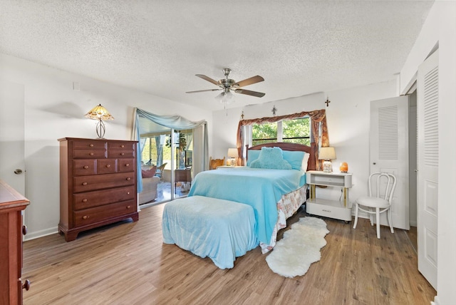 bedroom with multiple windows, hardwood / wood-style floors, a textured ceiling, and access to exterior