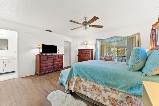 bedroom with ceiling fan, connected bathroom, a textured ceiling, and light hardwood / wood-style floors