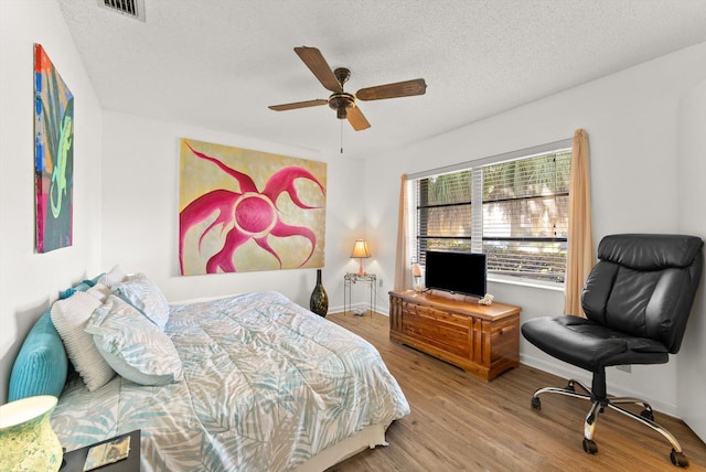 bedroom featuring hardwood / wood-style floors, a textured ceiling, and ceiling fan