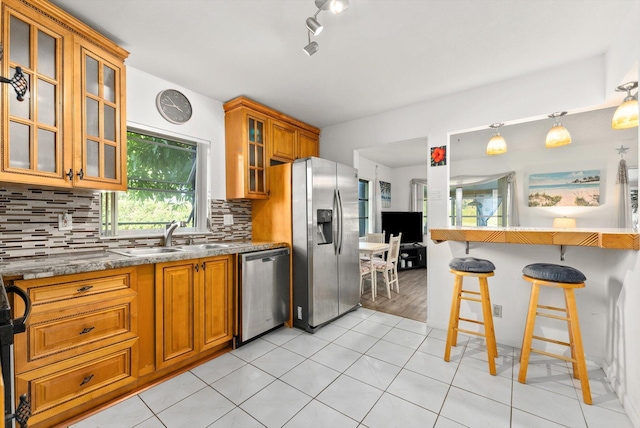 kitchen featuring sink, stainless steel appliances, decorative backsplash, a kitchen bar, and decorative light fixtures