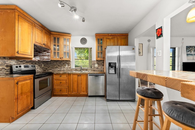 kitchen with backsplash, stainless steel appliances, sink, and light tile patterned flooring