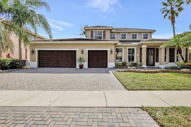 prairie-style home with central AC unit, stucco siding, a tiled roof, decorative driveway, and a front yard