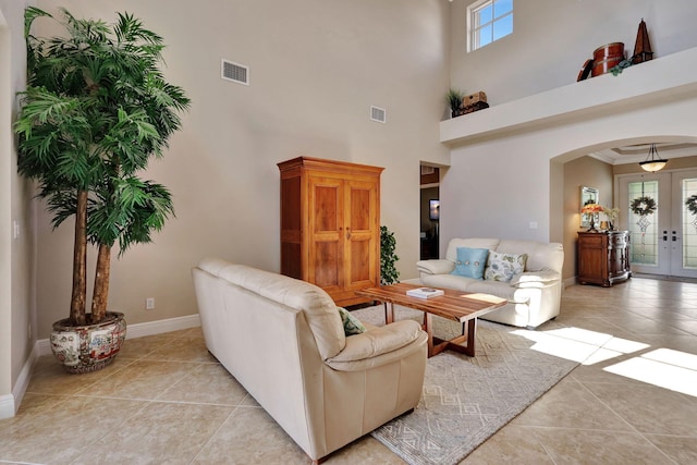 living room with light tile patterned floors, visible vents, arched walkways, and french doors