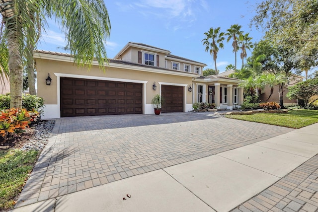 view of front of home with a garage, decorative driveway, and stucco siding