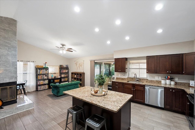 kitchen with lofted ceiling, sink, a breakfast bar area, a center island, and stainless steel dishwasher